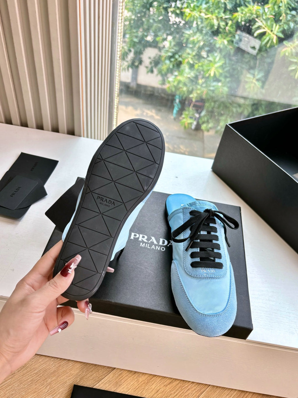 Prada women's light blue sneakers with black lace-up design and textured rubber outsole