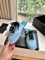 Prada women's light blue lace-up sneakers shown in hand, side profile with black laces