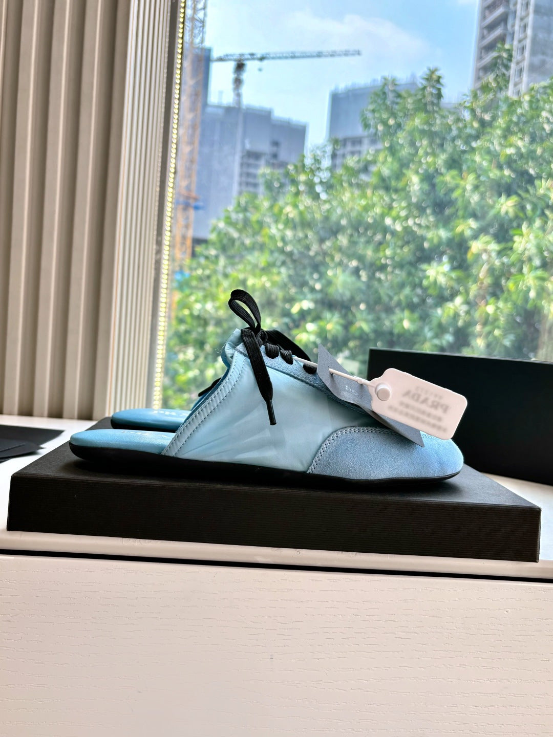 Prada women's light blue lace-up sneakers with black laces and dangling tag