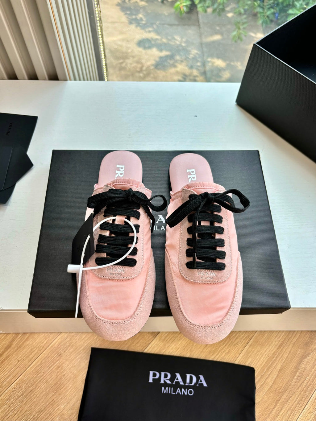 Prada lace-up sneakers for women, pink suede with black laces, front view pair