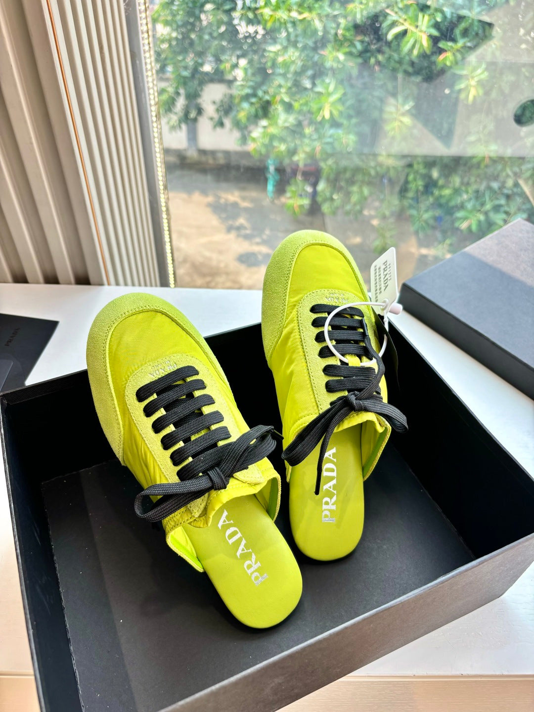 Neon yellow lace-up sneakers on black box, black laces and Prada logo detail