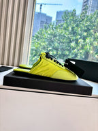 Neon yellow low-top sneaker with black laces, side view on black display base