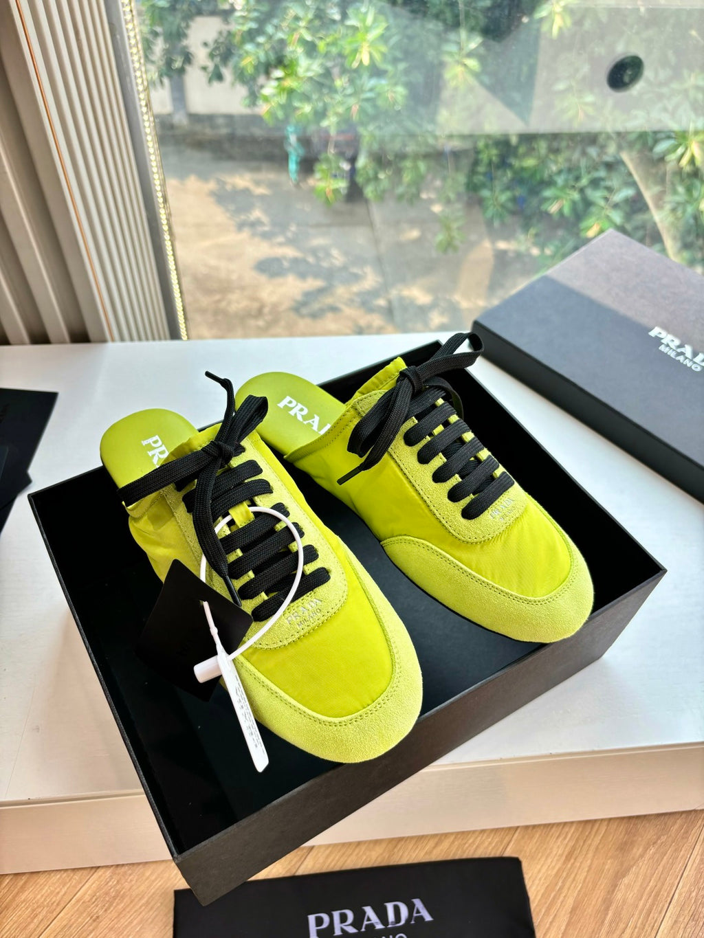 Neon yellow lace-up sneakers with black laces and textured panels, Prada branding