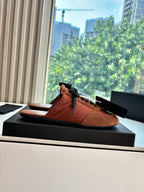 Prada low-top sneakers on display, tan upper with black laces and suede sides