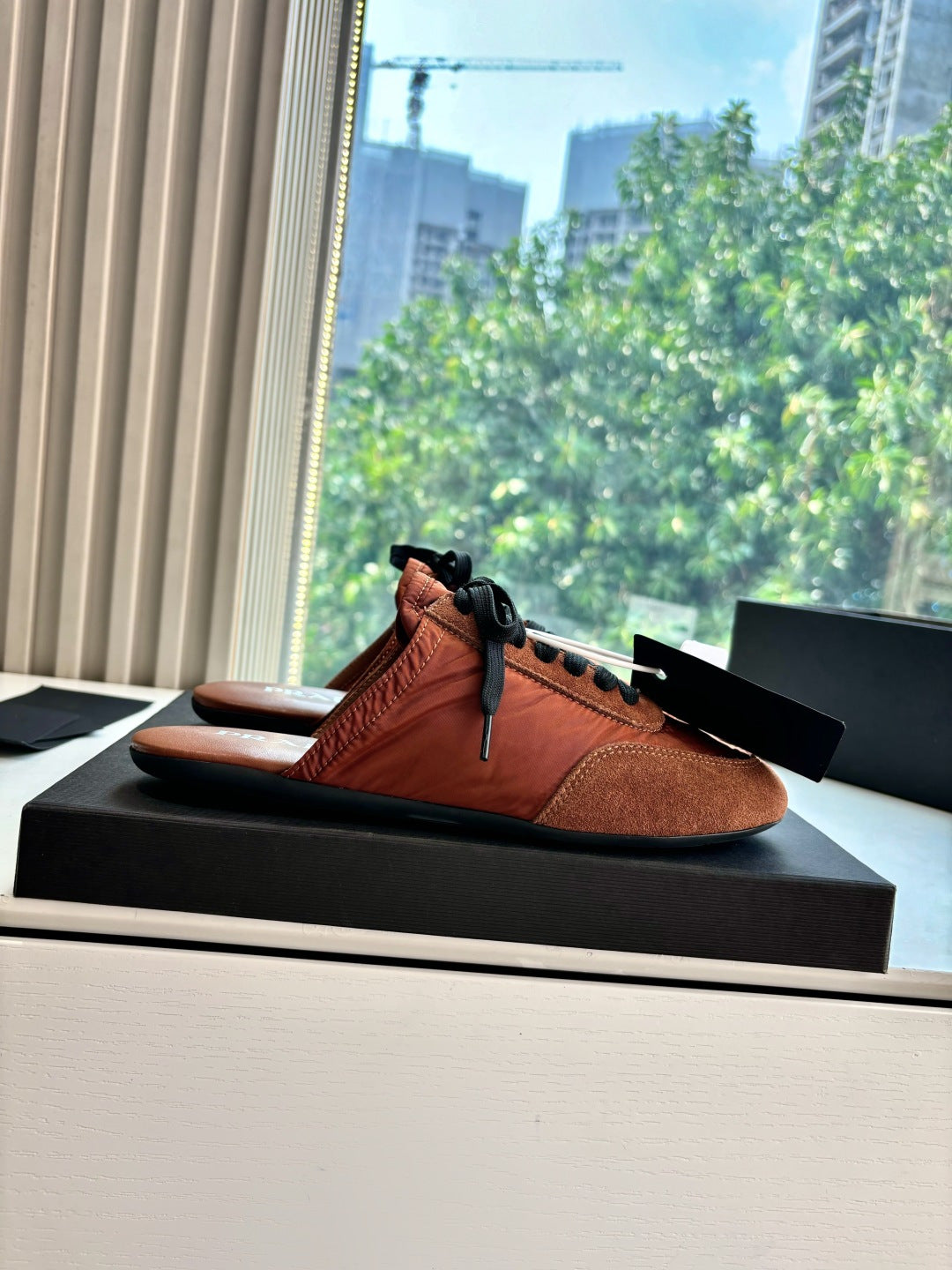 Prada low-top sneakers on display, tan upper with black laces and suede sides