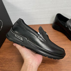 Prada unisex black leather loafer shown in hand, with strap and side logo badge