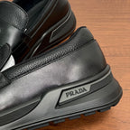 Prada unisex black leather loafer close-up of side logo plate and rubber sole