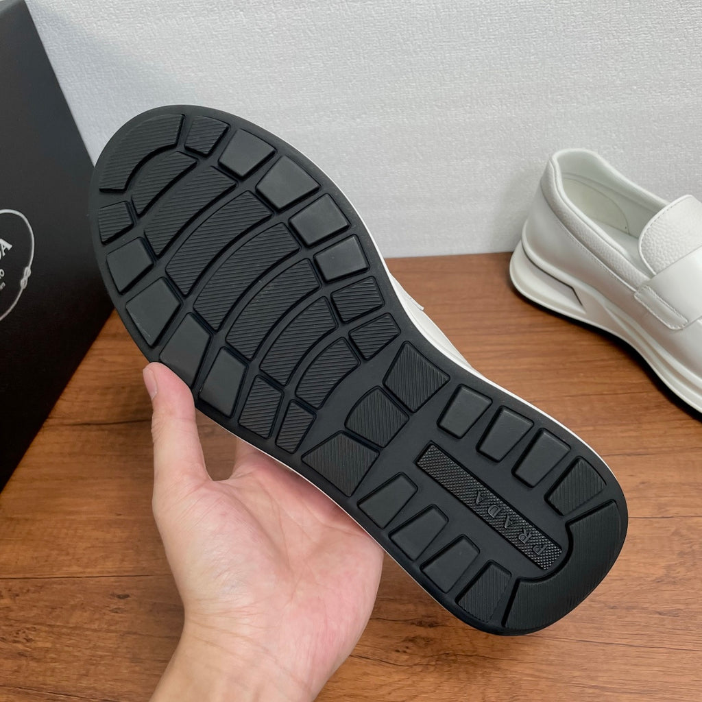 Black tread outsole of white Prada unisex slip-on sneakers