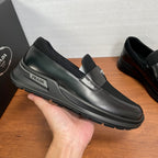 Prada unisex loafers shown in hand, black leather with metallic strap detail and chunky sole