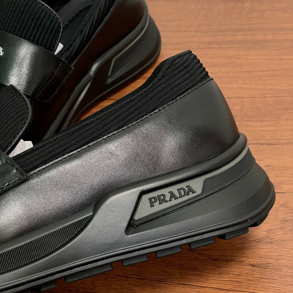 Prada unisex loafers side close-up, black leather with PRADA logo on chunky sole