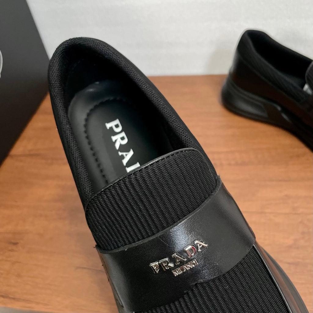 Prada unisex loafers instep view, black leather with ribbed elastic and PRADA logo strap