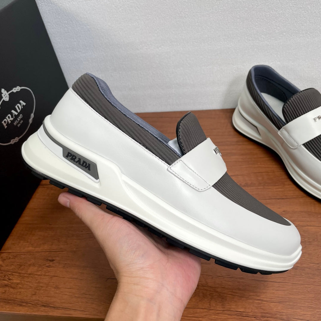 White slip-on sneakers with gray elastic panels and Prada label on side