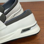 White slip-on sneaker side view with gray elastic band and Prada logo patch