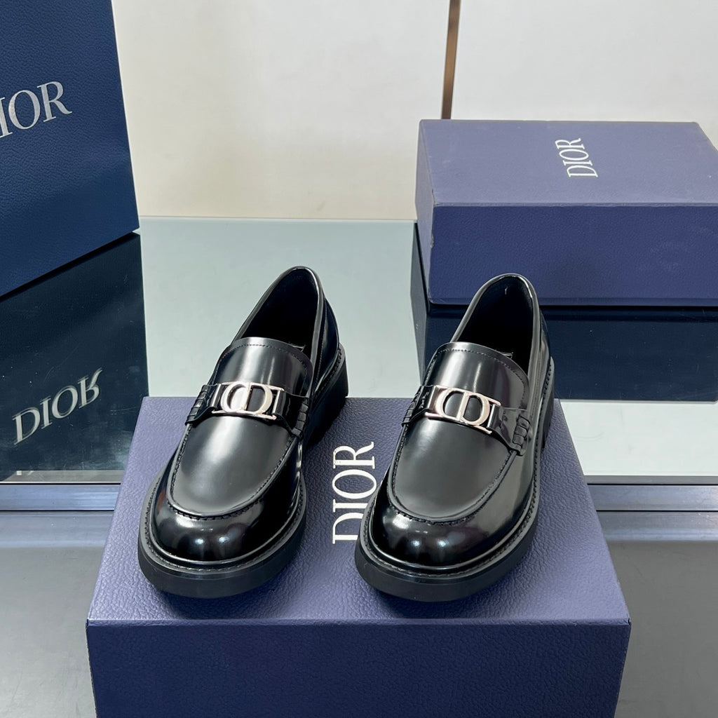 Pair of black leather unisex loafers with silver buckle accents and rounded toe
