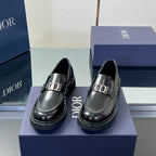 Pair of black leather unisex loafers with silver buckle accents and rounded toe