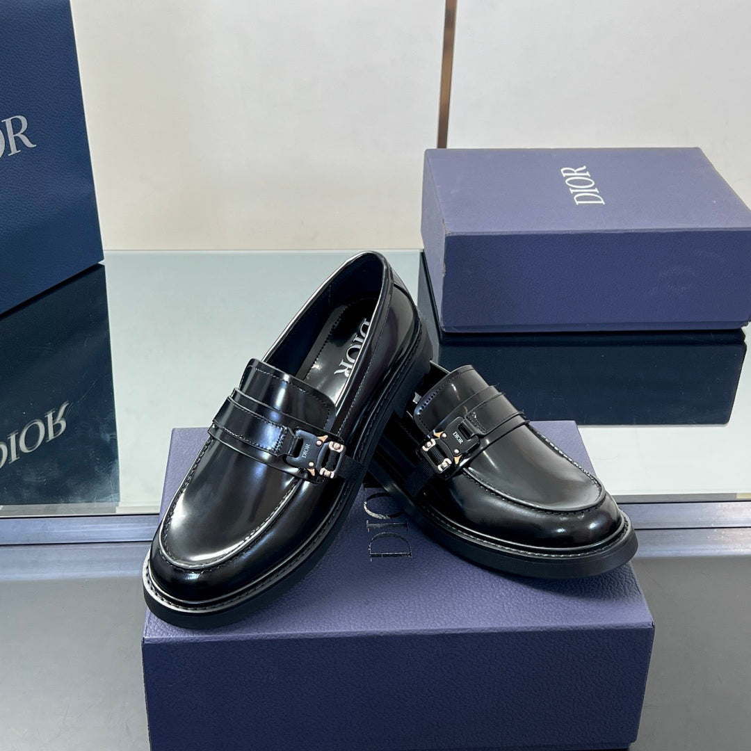 Black leather unisex loafers with metal buckle strap; stitched toe detail