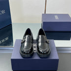 Black leather unisex loafers, front view with metal buckle strap and stitched toe