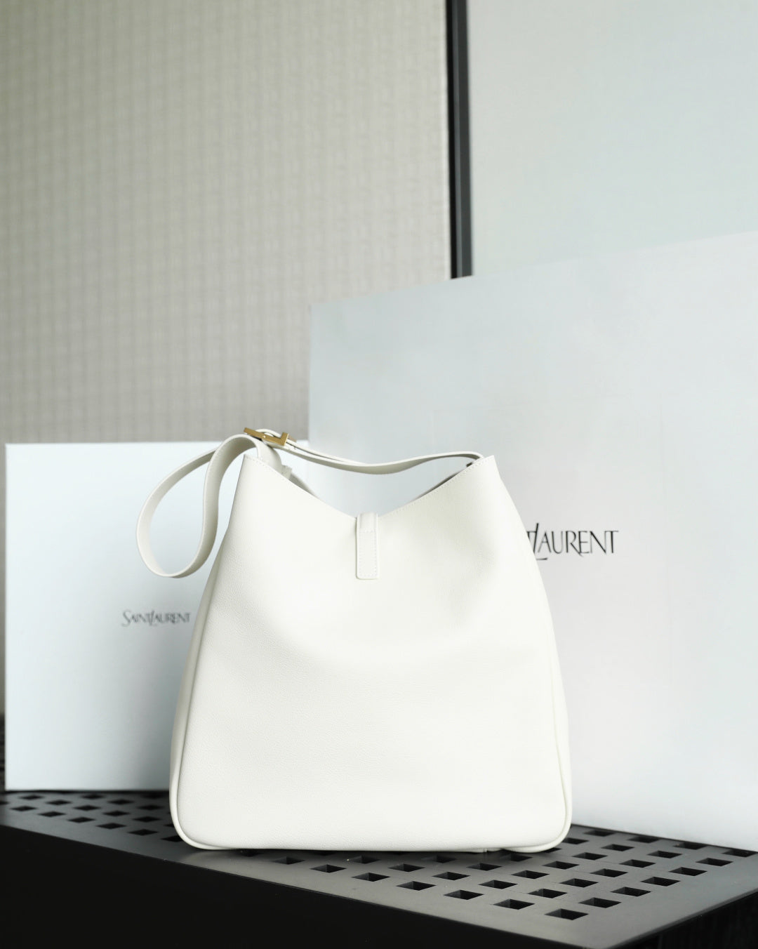 YSL bag in white leather with top loop handles and gold clasp hardware.