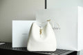 YSL bag in white leather with gold hardware and drawstring top.
