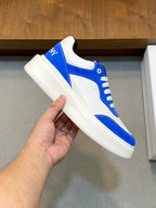 Blue and white low-top lace-up sneaker held in hand, side close-up