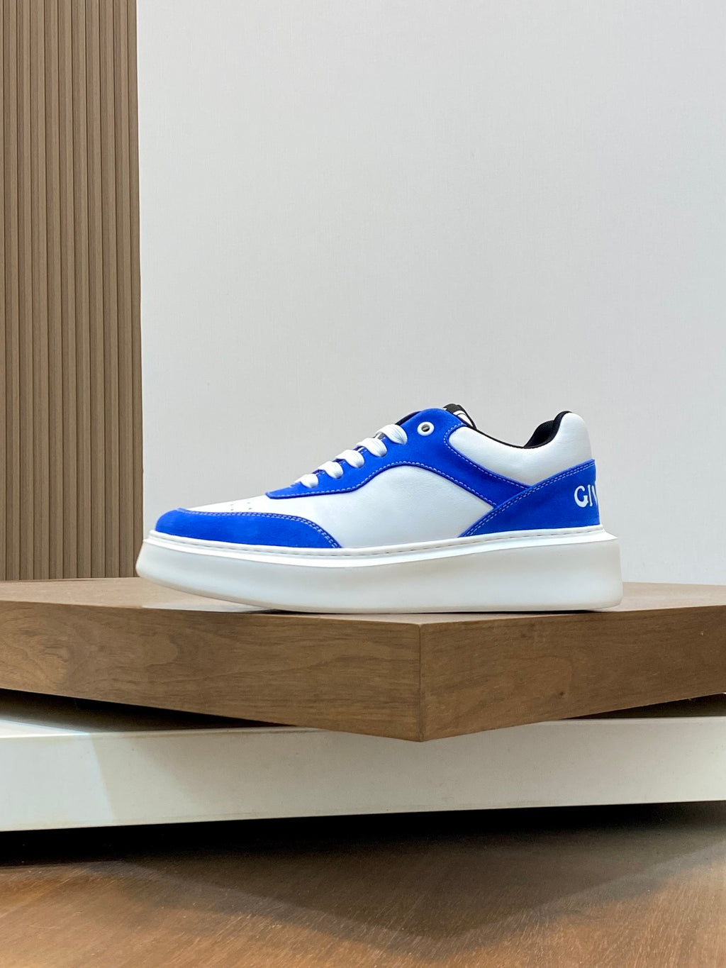 Blue and white low-top lace-up sneaker, side profile on display shelf