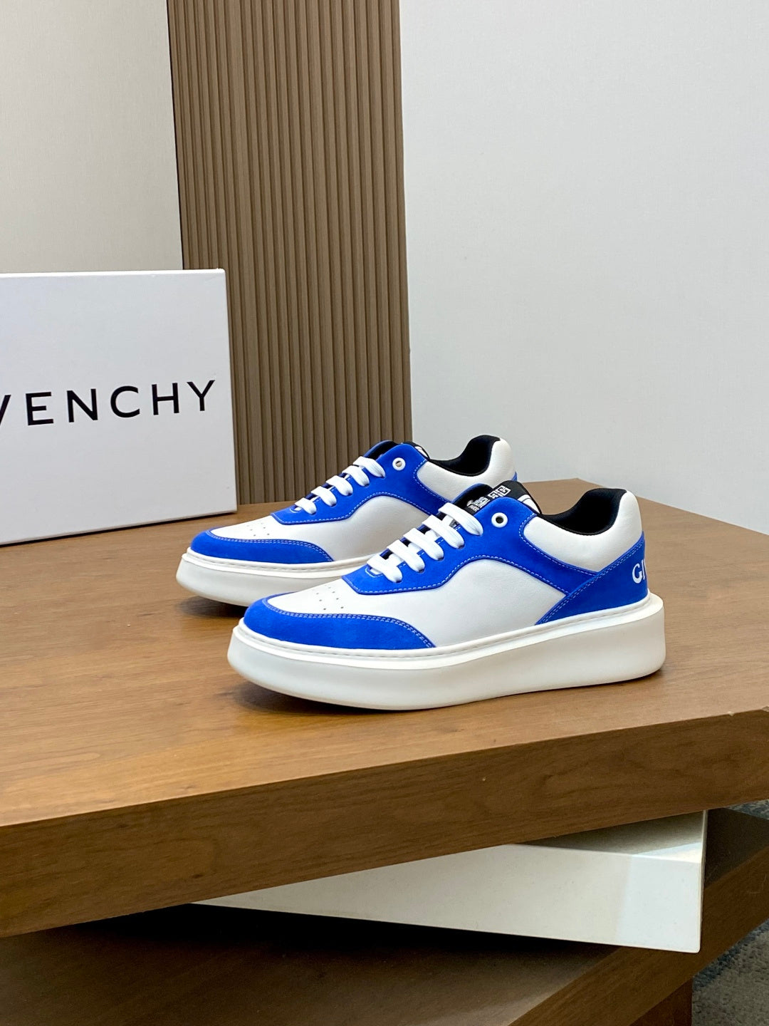 Blue and white low-top lace-up sneakers, pair angled on display shelf