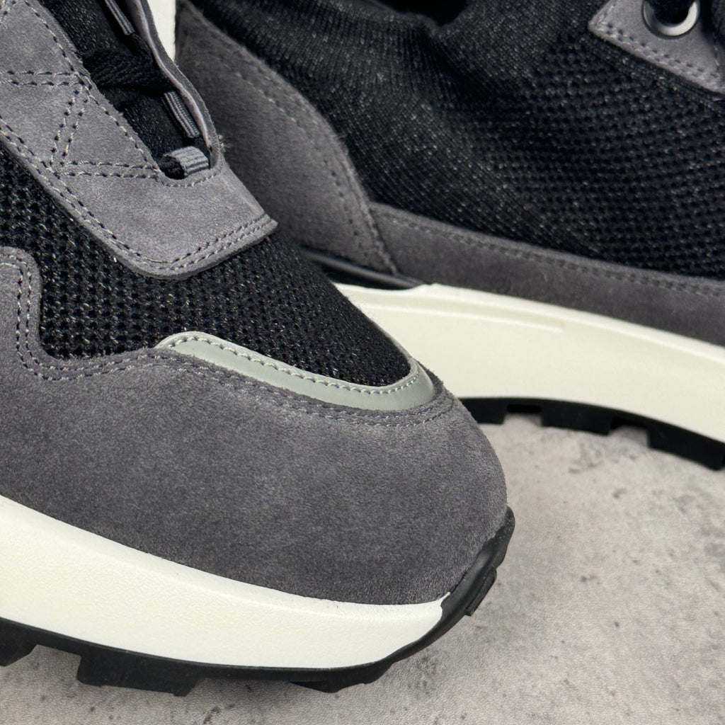 Close-up of dark gray suede and black mesh panels on a lace-up sneaker