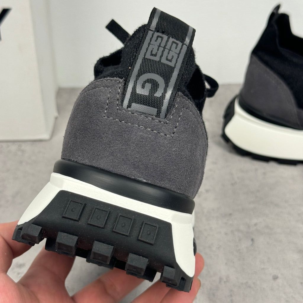 Back view of black sneaker outsole with tread and heel strap detail