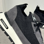 Close-up of black lace-up sneaker upper with dark gray trim and logo patch