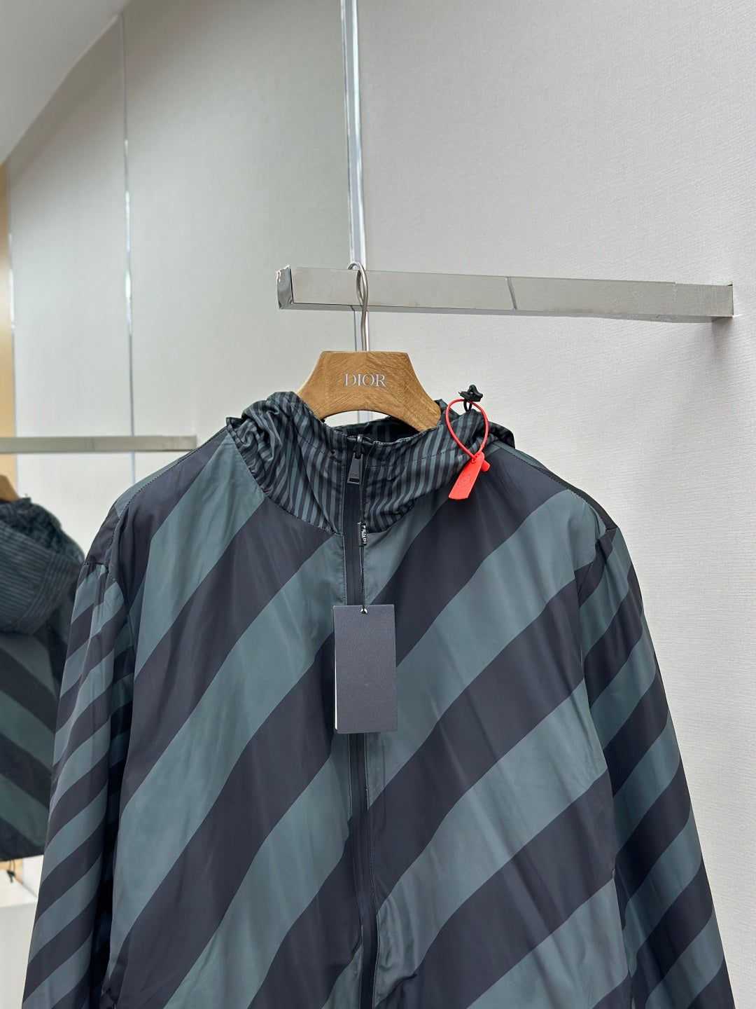 Hooded windbreaker jacket with diagonal stripe pattern and front zipper detail
