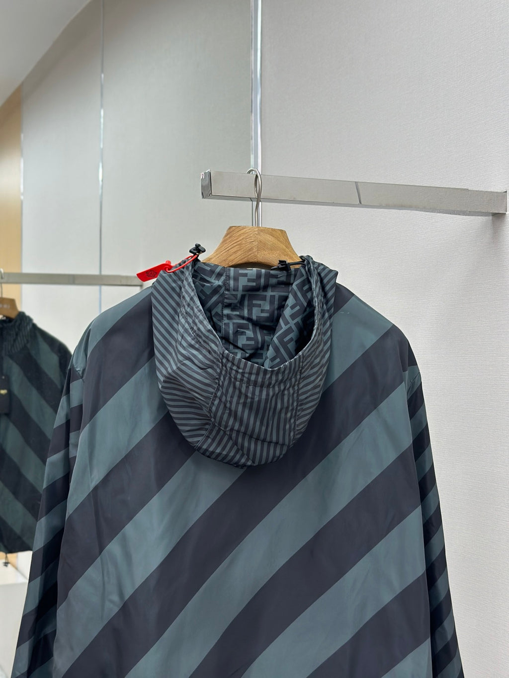 Hooded windbreaker jacket with diagonal stripes; close-up of hood and zipper