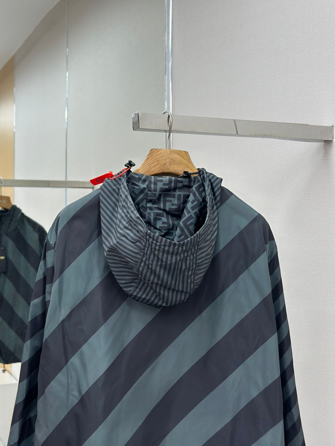 Hooded windbreaker jacket with diagonal stripes; close-up of hood and zipper