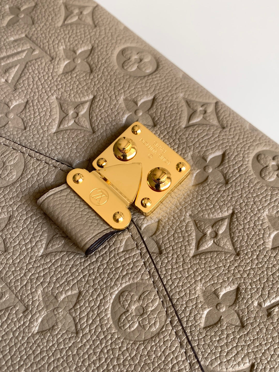 Louis Vuitton monogram leather flap close-up with gold clasp and textured surface