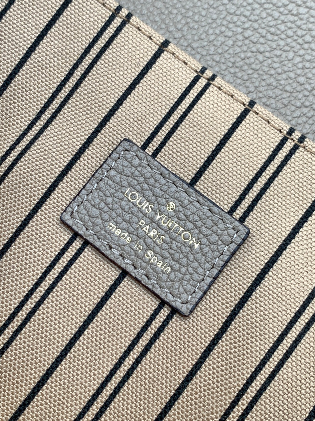 Louis Vuitton Paris label on striped fabric lining with gray text on light background