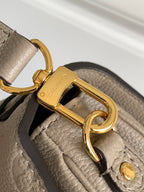 Louis Vuitton monogram bag hardware close-up: gold D-ring and clasp on taupe leather