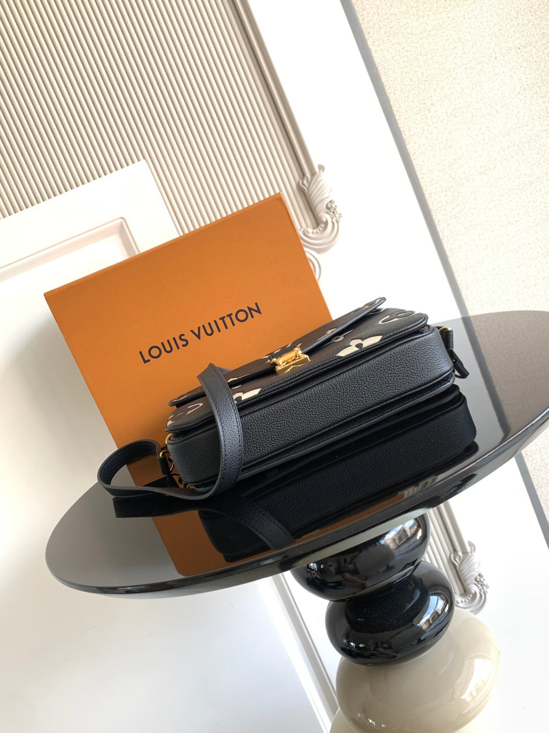 Louis Vuitton small crossbody bag in dark navy with gold buckle and layered flap design.
