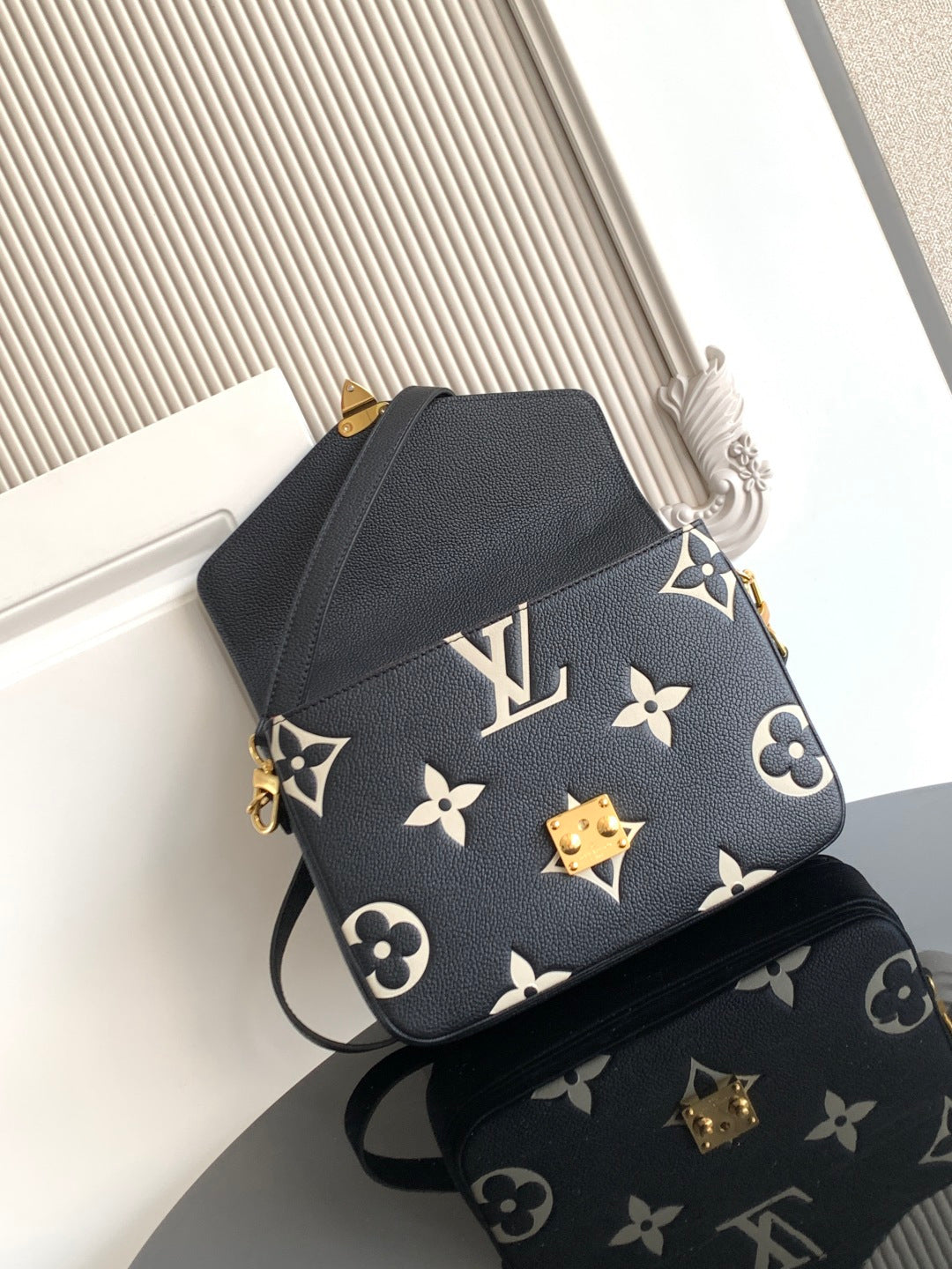 Louis Vuitton monogram crossbody bag in dark navy with gold emblem and adjustable strap.