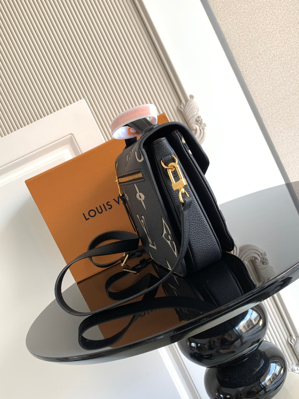 Louis Vuitton monogram crossbody bag with structured black leather, gold clasp, and strap.