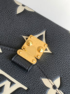 Louis Vuitton flap clasp detail on dark pebbled leather with gold hardware and monogram accents.
