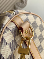Louis Vuitton checkerboard bag close-up with gold clasp and tan leather trim