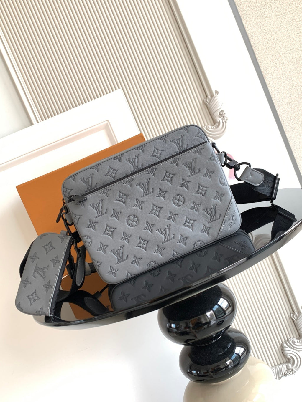 Louis Vuitton monogram crossbody bag, gray with black shoulder strap and logo print.