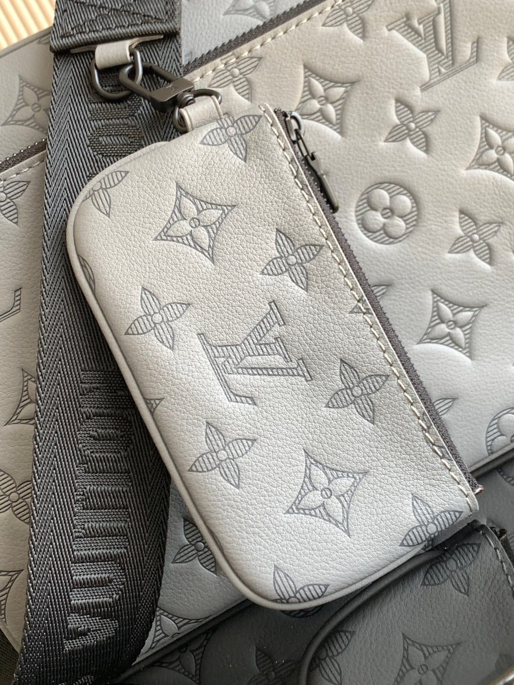 Louis Vuitton monogram pouch, light gray leather with zipper and logo pattern close-up.