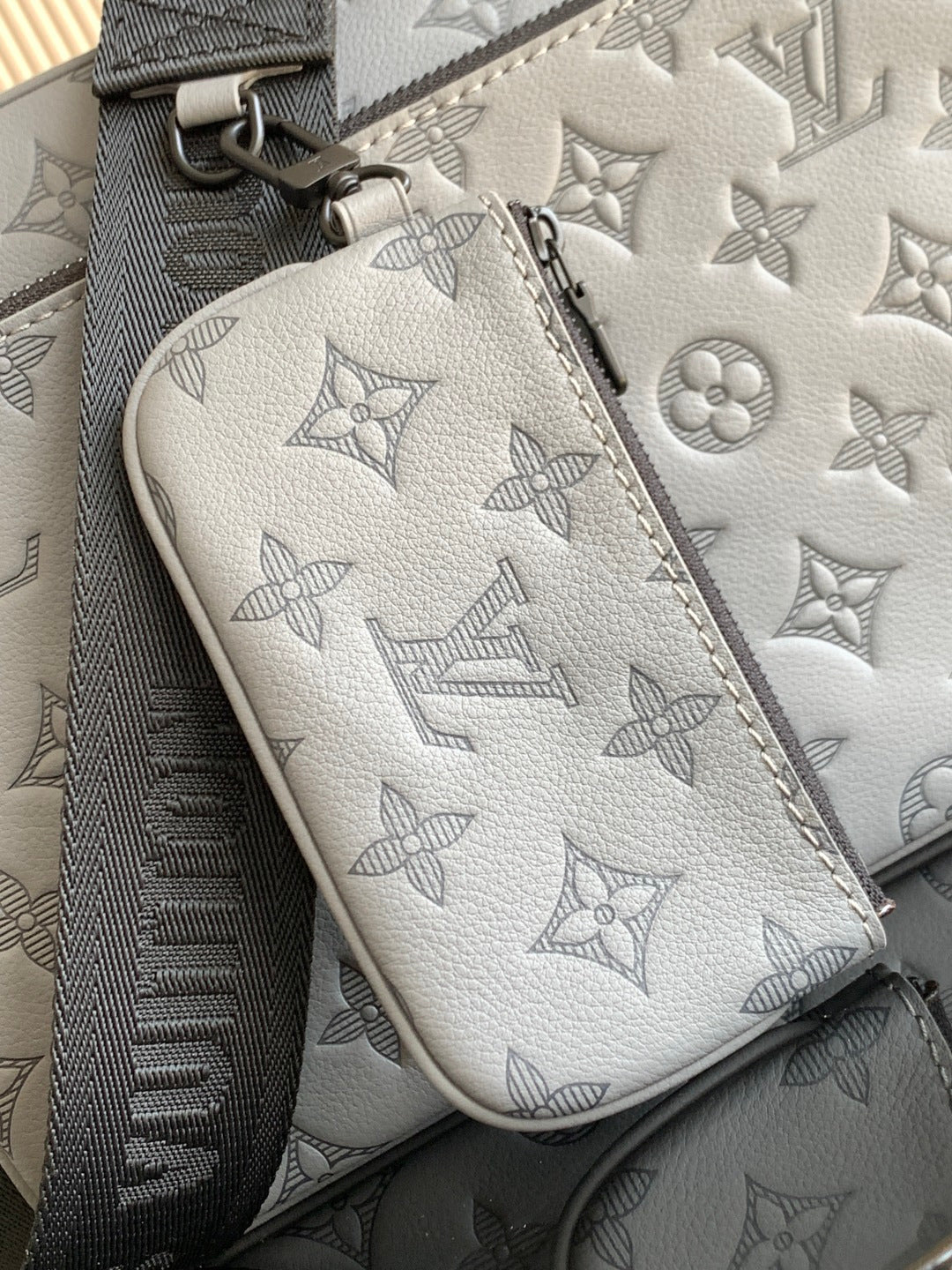 Louis Vuitton monogram pouch, light gray leather with zipper and logo pattern close-up.