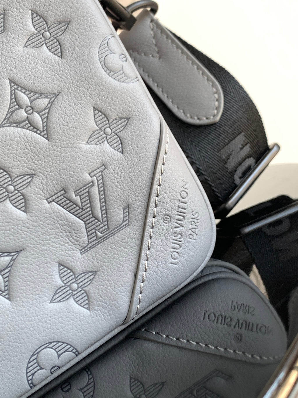 Louis Vuitton monogram leather wristlet, textured gray with embossed logo pattern.