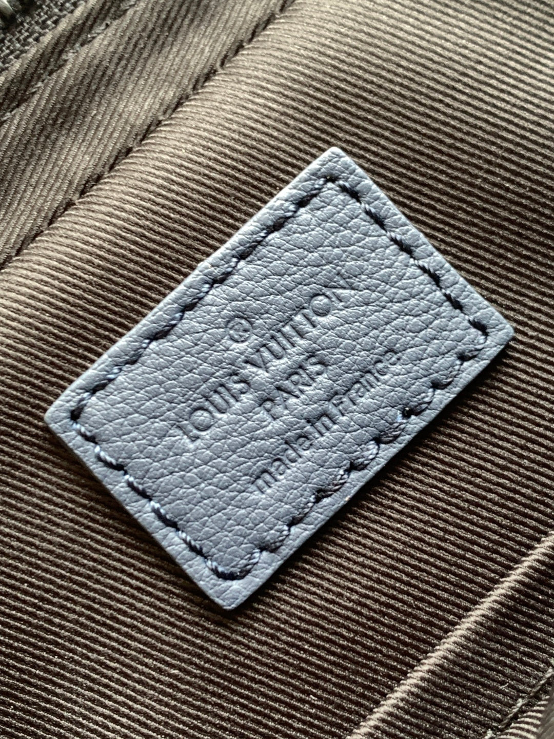 Louis Vuitton blue leather interior label with embossed text