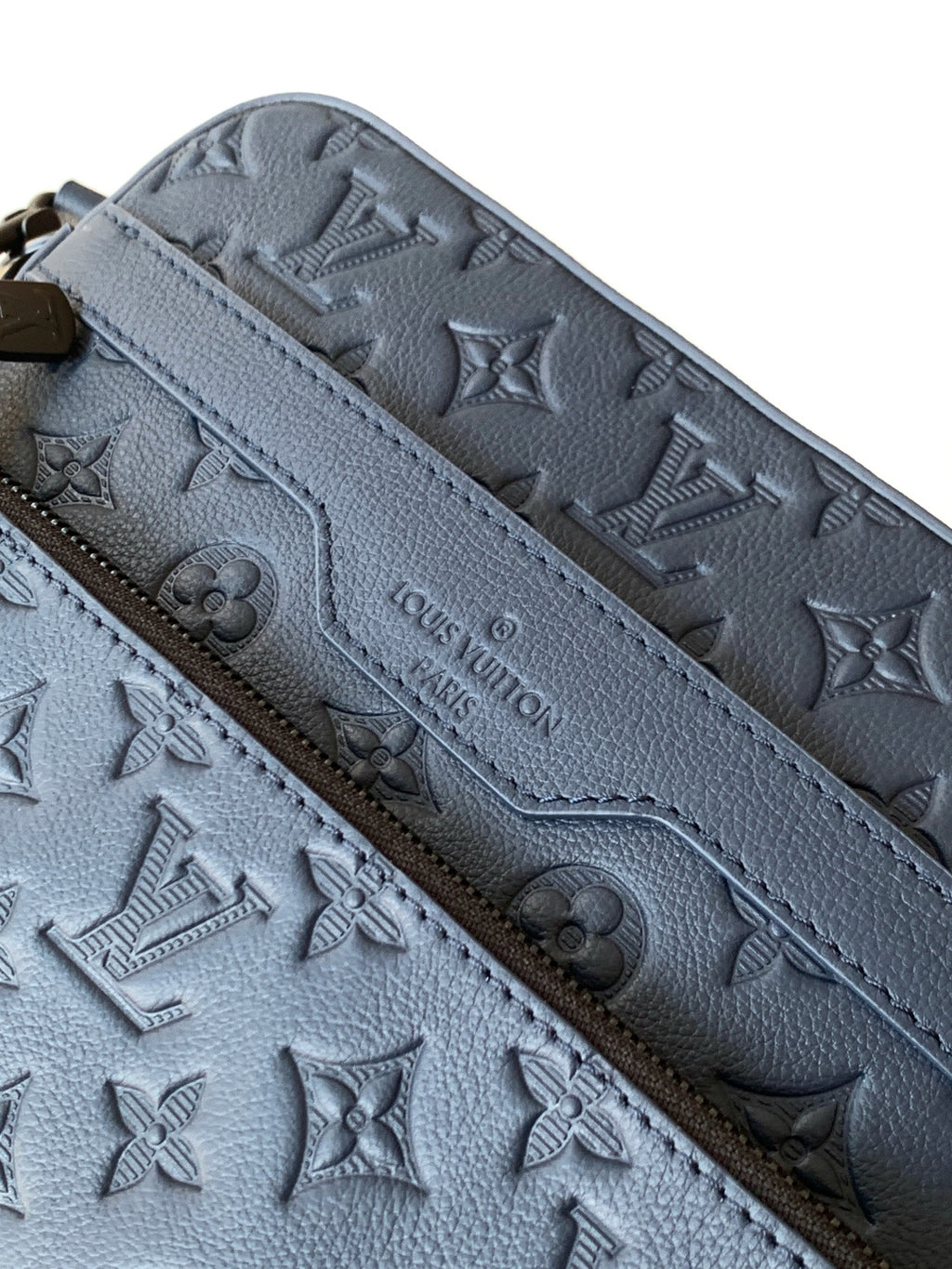 Dark blue leather crossbody bag close-up of embossed monogram pattern