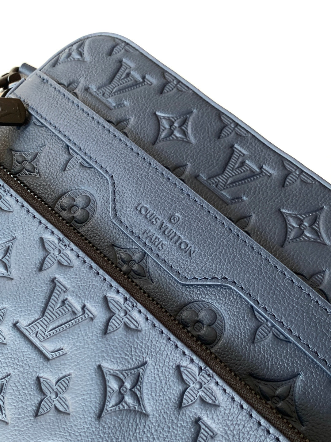 Dark blue leather crossbody bag close-up of embossed monogram pattern
