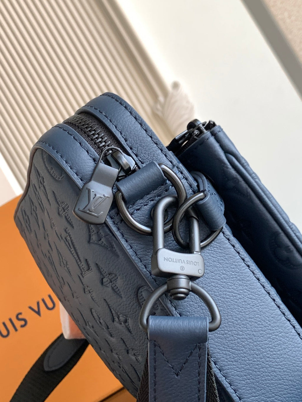 Dark blue crossbody bag close-up of strap hardware and top clasp