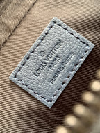 Dark blue crossbody bag interior label with embossed logo text