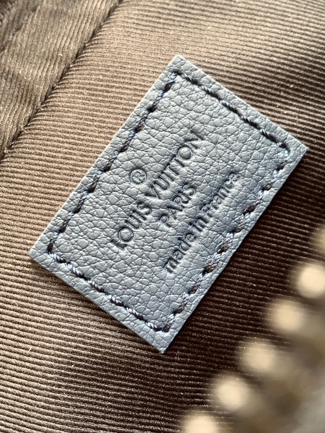 Dark blue crossbody bag interior label with embossed logo text